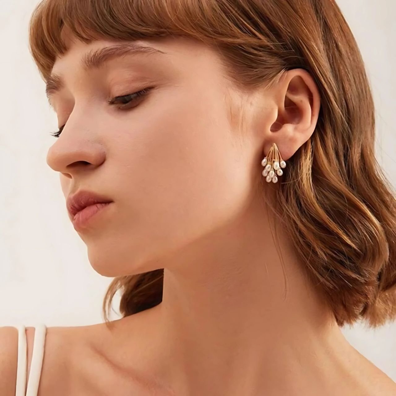 pearl drop earrings peacock design worn by woman